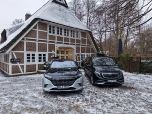Luxus Mercedes-Maybach Fahrzeuge vor traditionellem Reetdachhaus im Winter