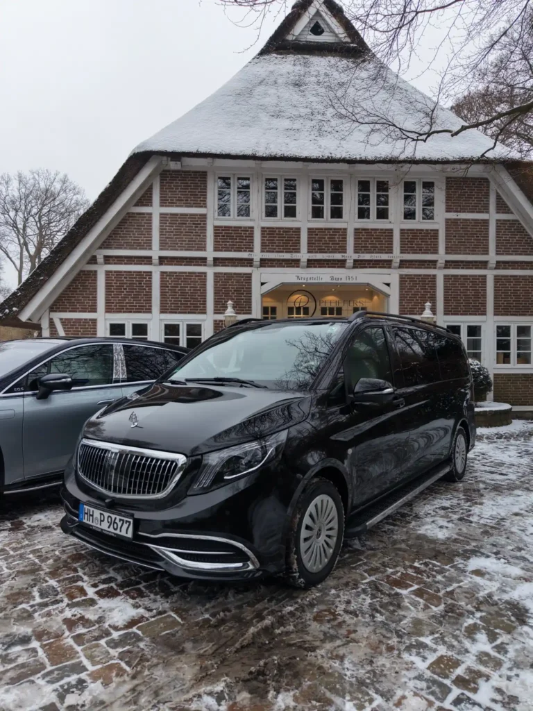Mercedes-Maybach Luxus-Van vor traditionellem Reetdachhaus mit Schnee